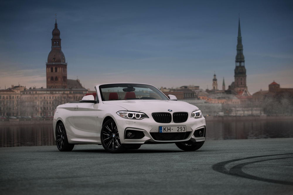 This is a white convertible BMW 2-Series on a mountain road.