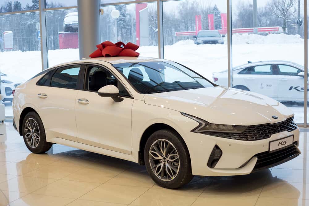 This is a white 2021 Kia K5 on display at a car dealership.