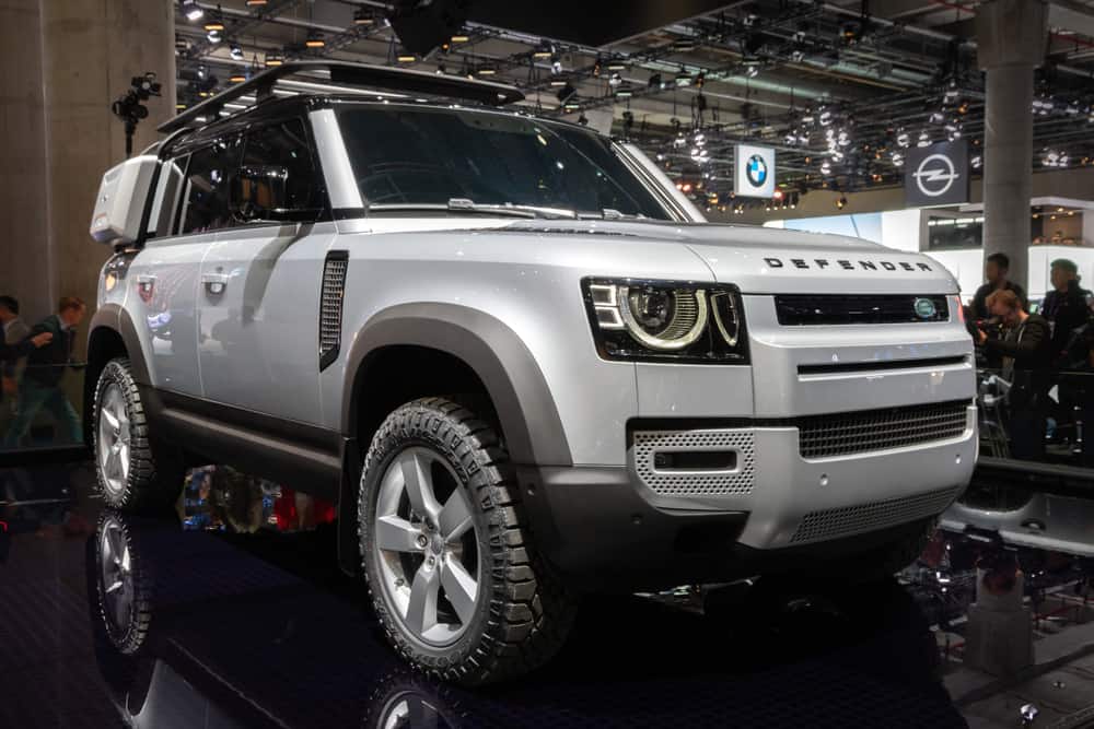 This is a silver Land Rover Defender on display at a car show.