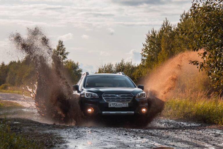 This is a Subaru Outback on a dirt road with mud.