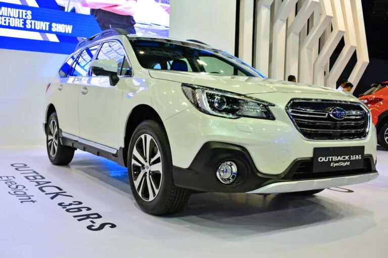 This is a white Subaru Outback on display at a car show.