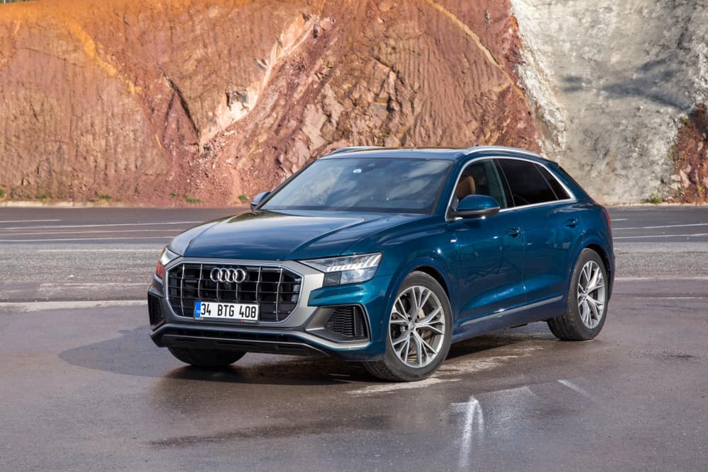 Distant view of a blue Audi Q8 parked on a mountain road.