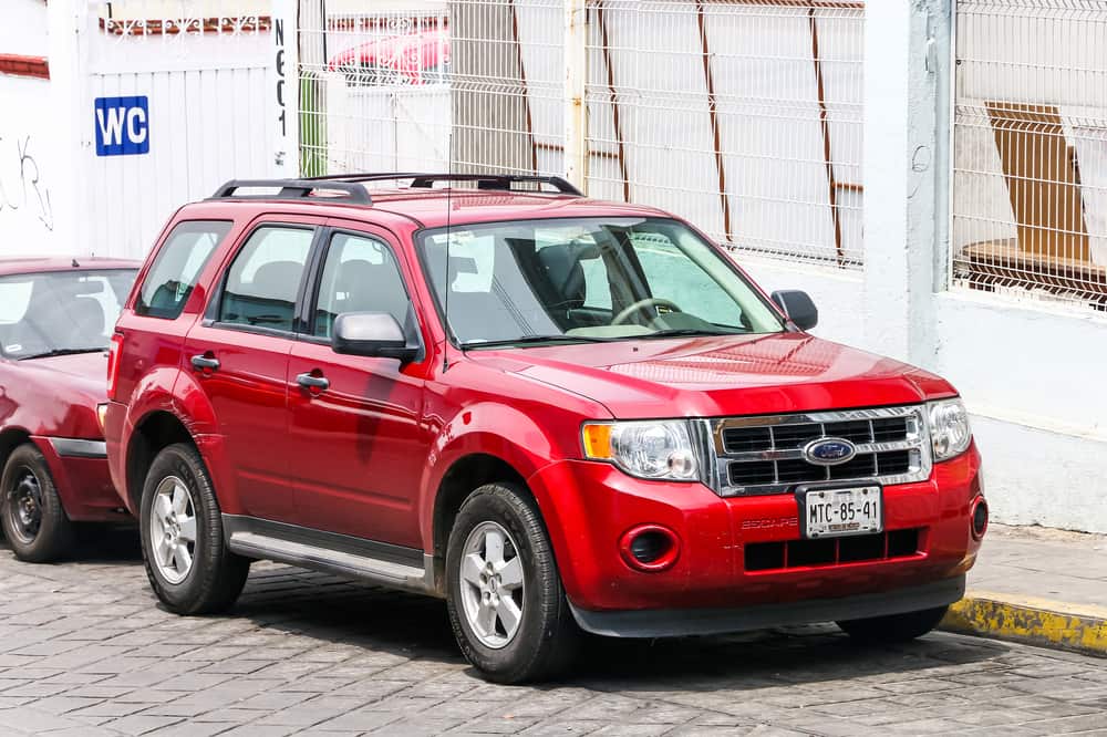 This is a red Ford Escape parked on the side of a street.