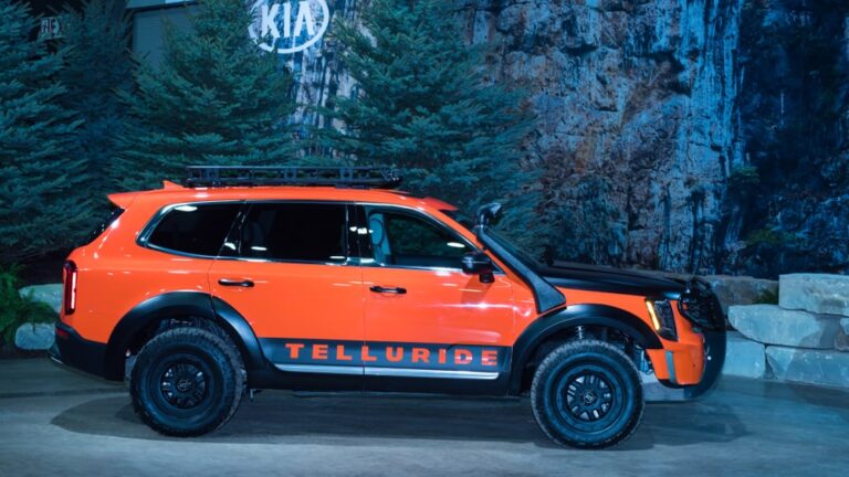 This is an orange Kia Telluride on display at a car show.