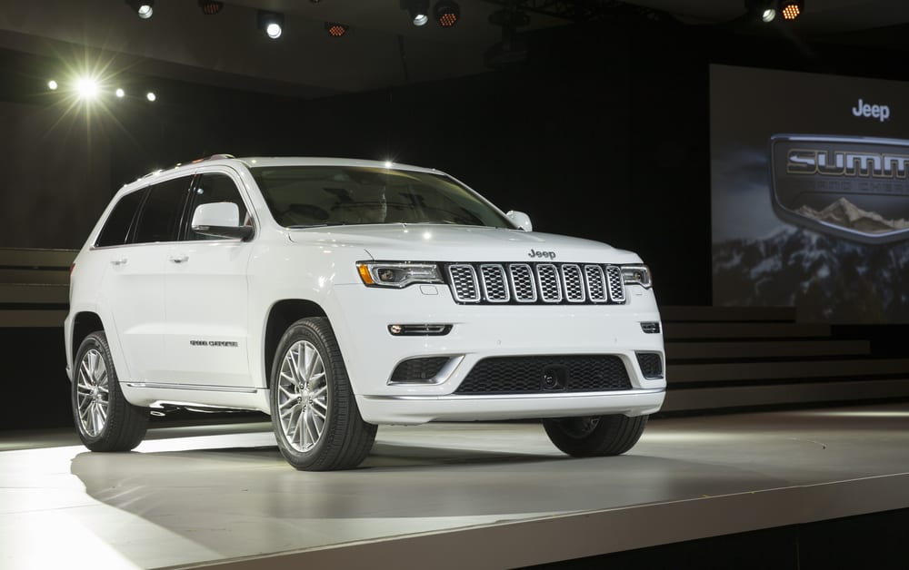 This is a white Jeep Grand Cherokee displayed on a platform at the car show.