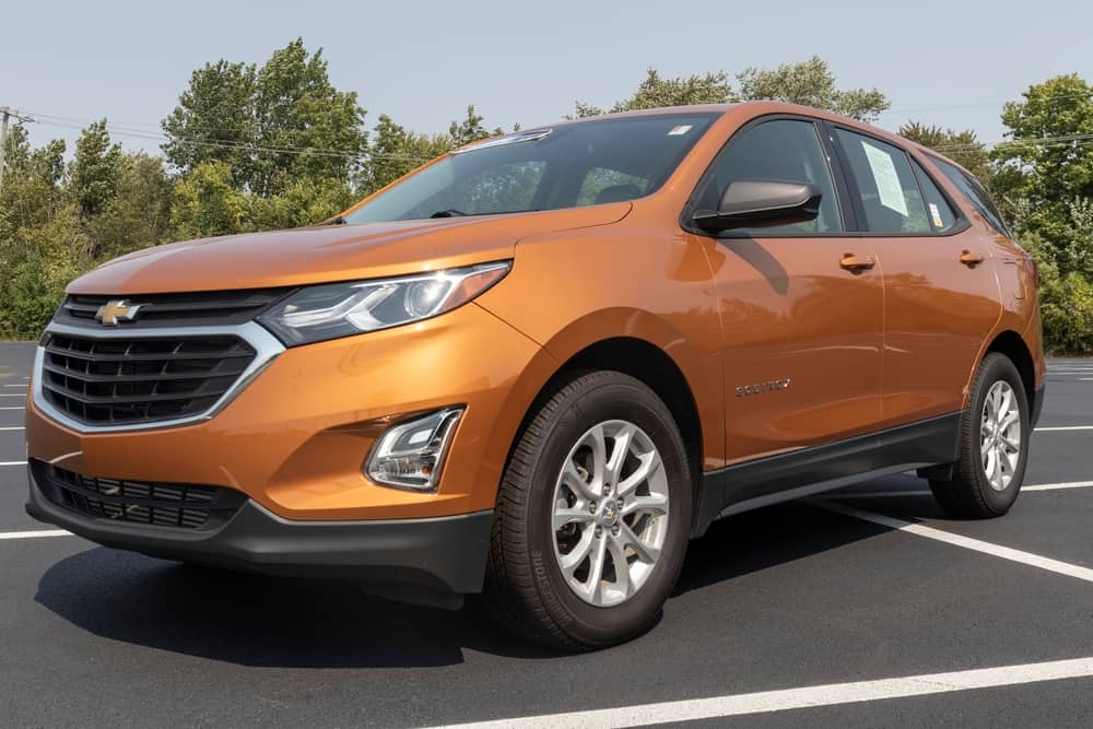 This is an orange Chevrolet Equinox parked at an open area parking lot.