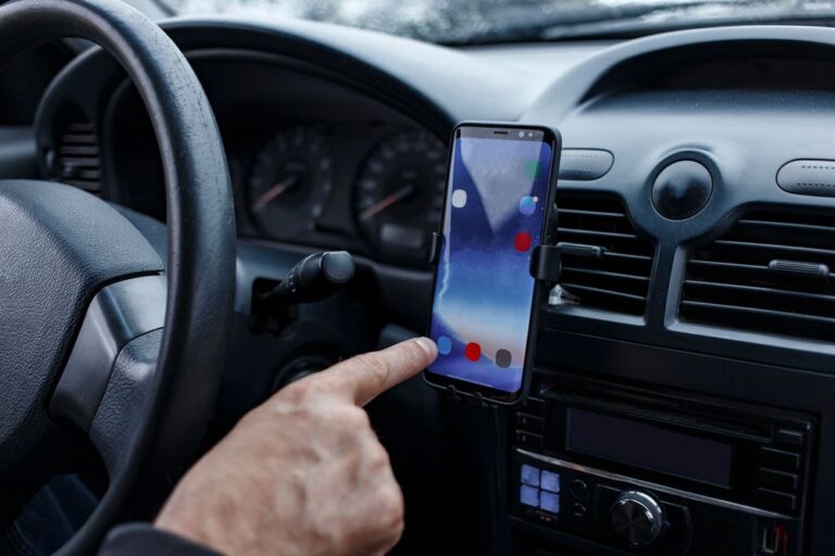 Driver in the car uses smartphone mounted in a car holder.