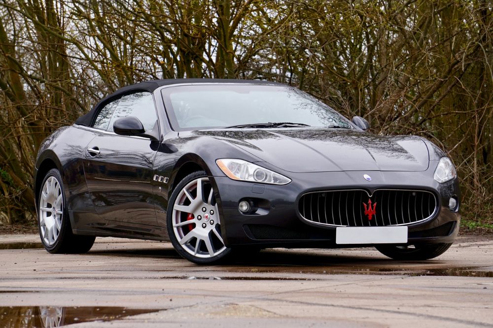 Front and side shot of a black Maserati MC20 parked outside.