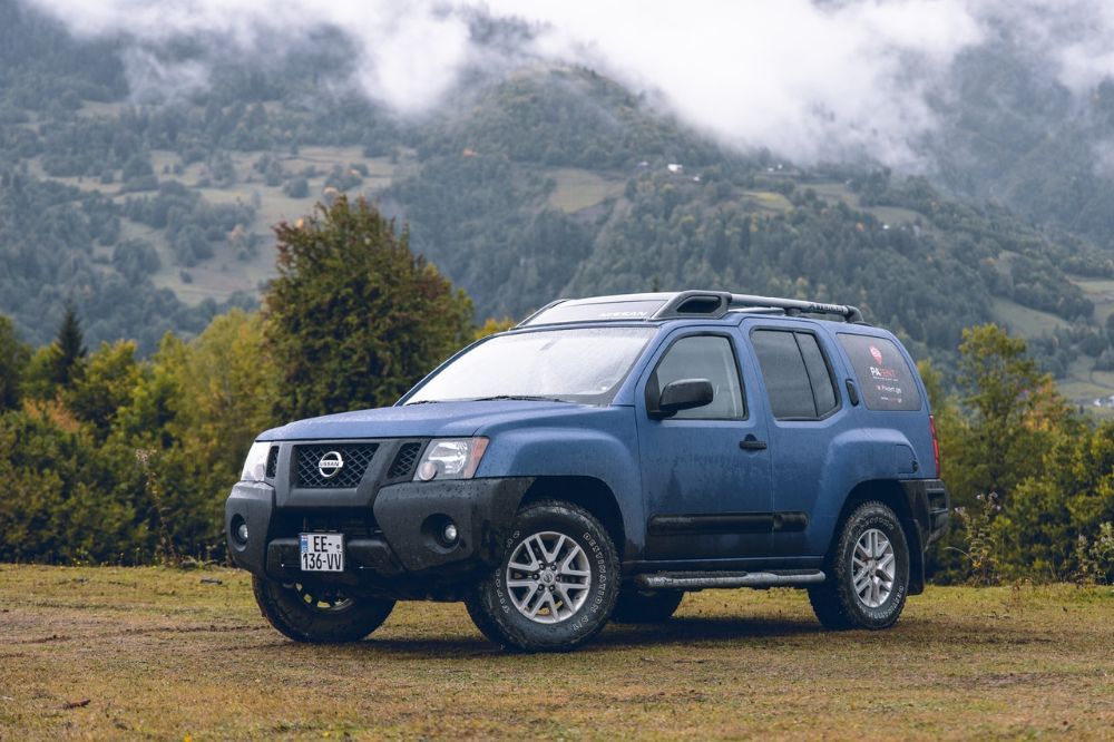 Blue Nissan pathfinder on mountain slope area.