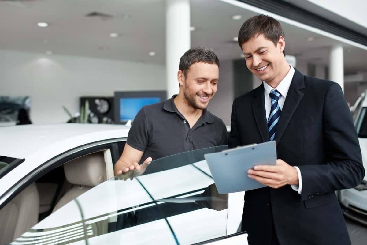 Salesman talking to the buyer in car showroom.