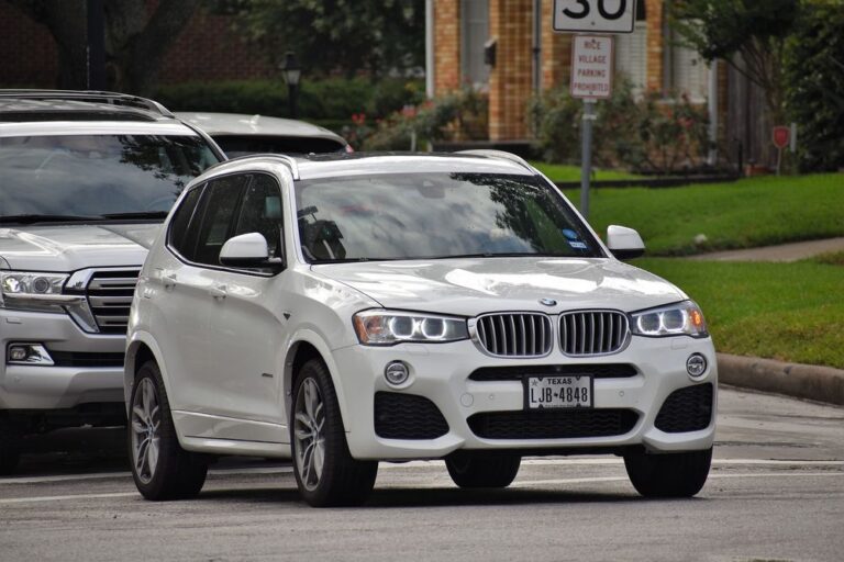 White BMW X5 driving on road.