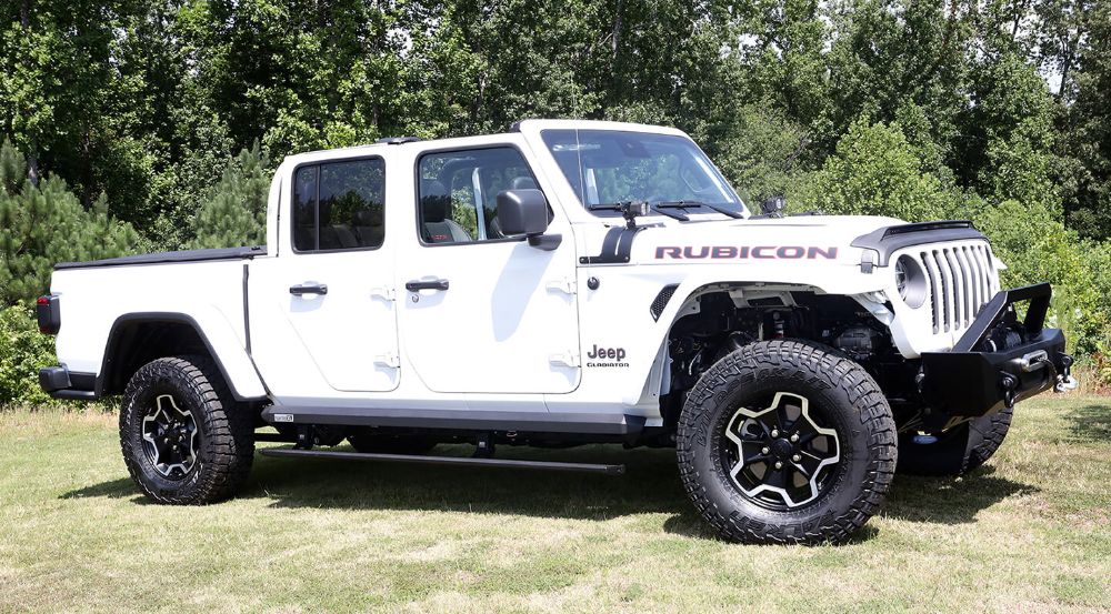 White jeep wrangler on lush greenery area.