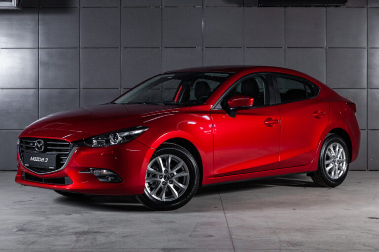 A red Mazda3 with a gray tile background.