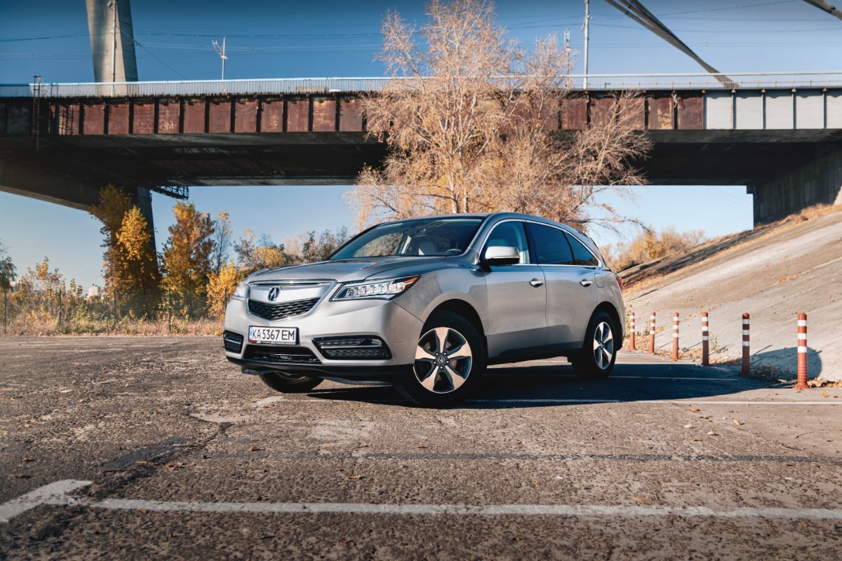 Side view look of a silver car under the bridge.