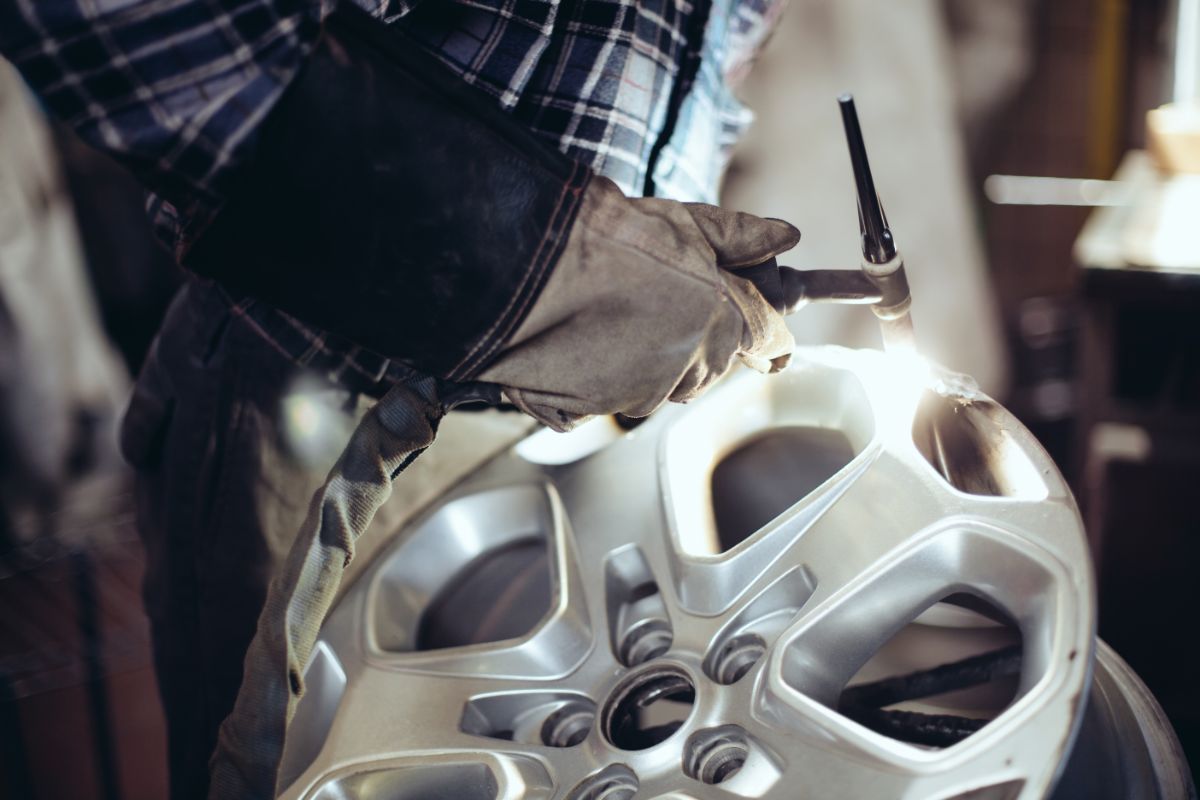 Man working on alloy wheel.