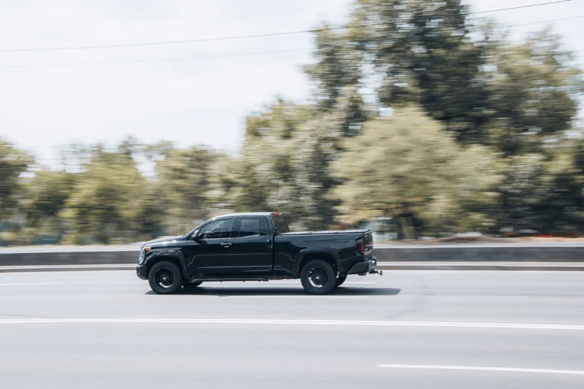 A black toyota car on the road speeding up.