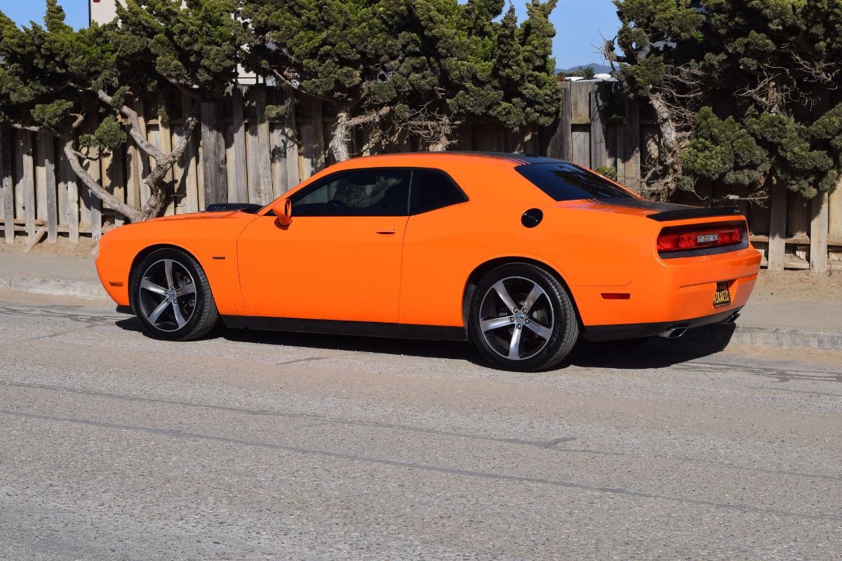 Lighted spoiler of bright orange Chevy sports car parked outside.