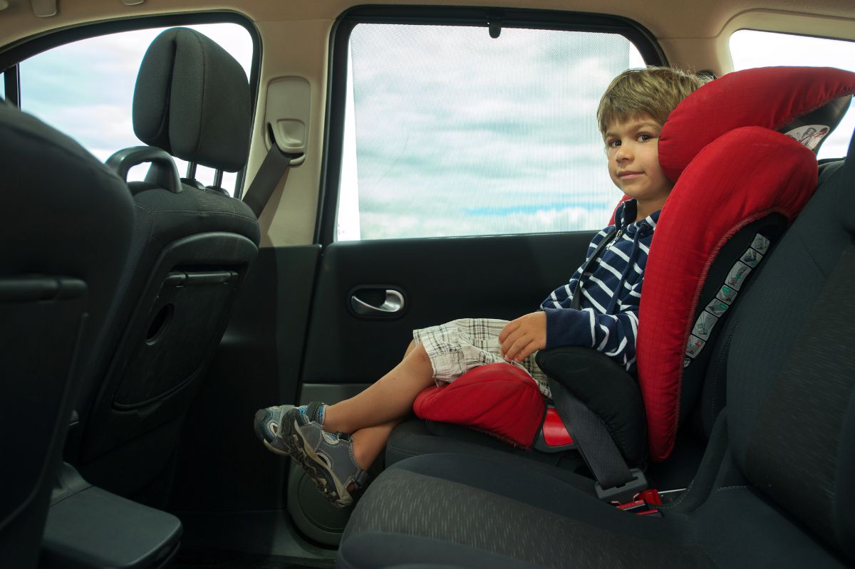 Little boy sitting in high back booster car seat.