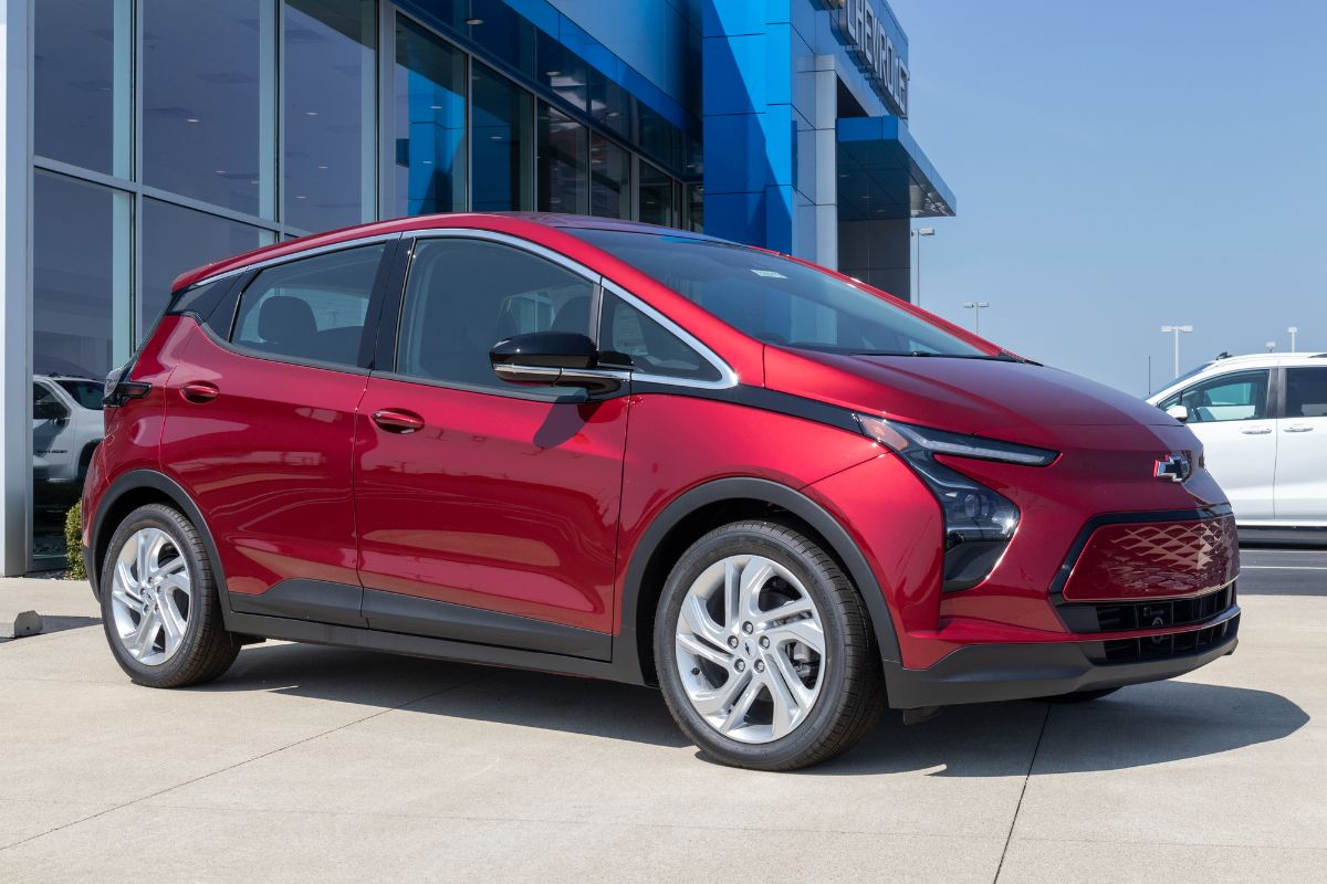 Side view of maroon Chevrolet Bolt parked close to building.