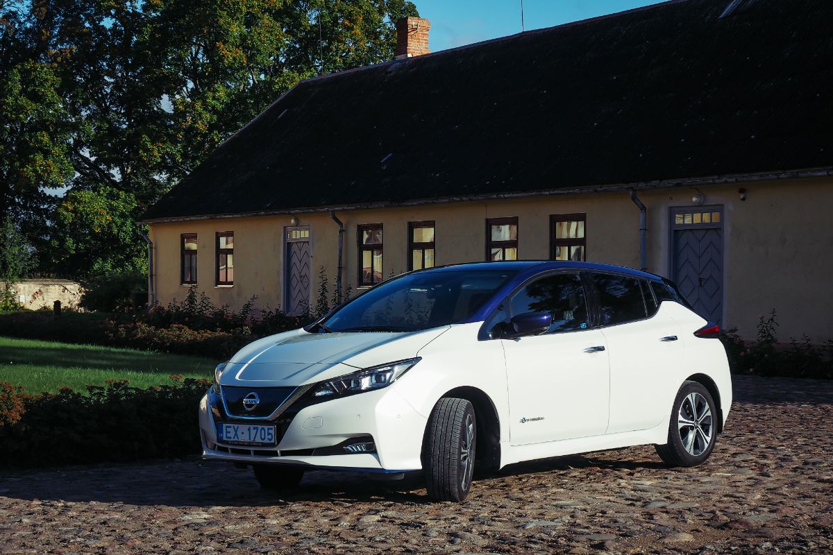 Side view shot of a white car infront of the house.