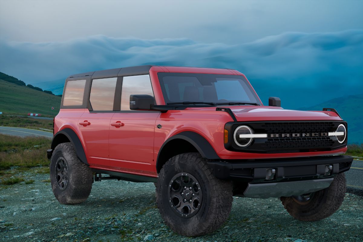 Front view of red Ford Bronco on sloppy mountain area.