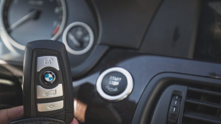 Driver holding remote door key fob on car.