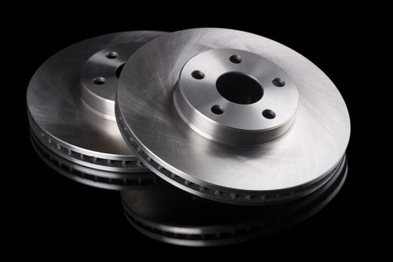 Steel blank and smooth brake rotor in black background.