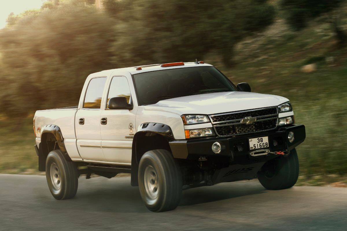 A white chevy silverado on the road moving.