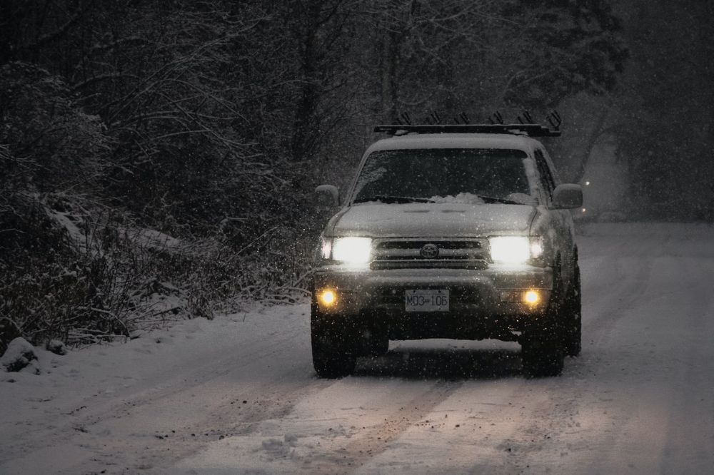 White Toyota Tundra car is driving down on the patchy ice roadway.