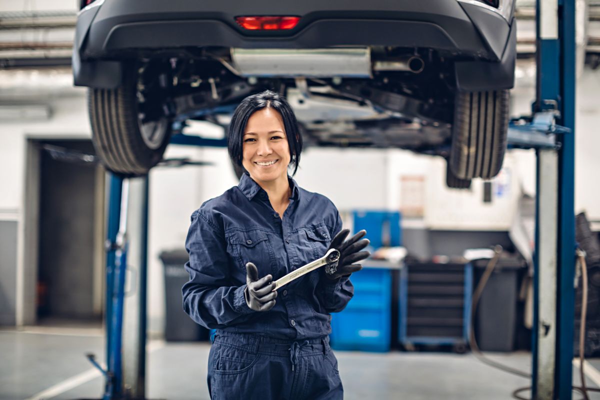 Woman mechanic holding tool at auto repair shop.