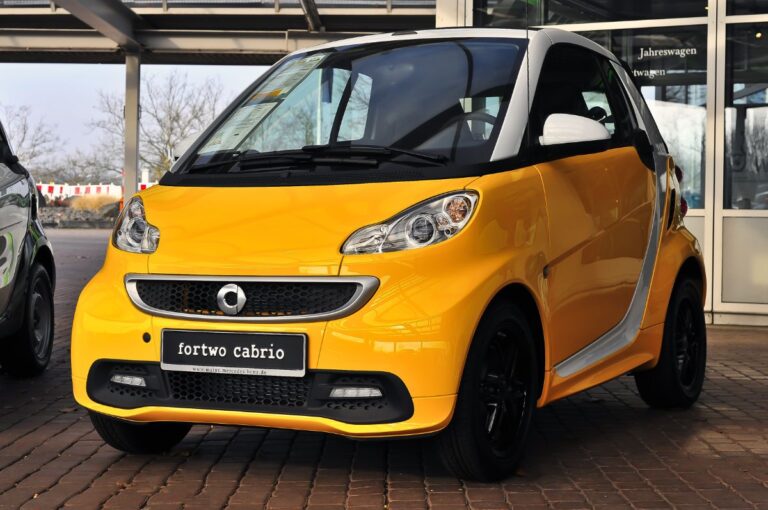 Front side view of of a yellow smart car.