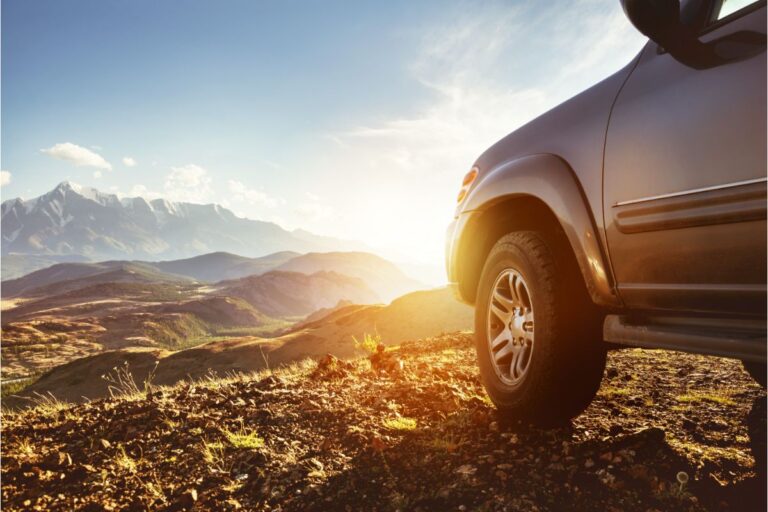 A photo of car facing the mountains and sunset.