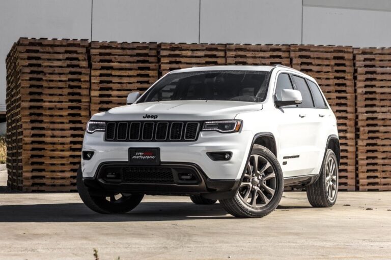 A photo of a white SUV near a stacked pallet boards.