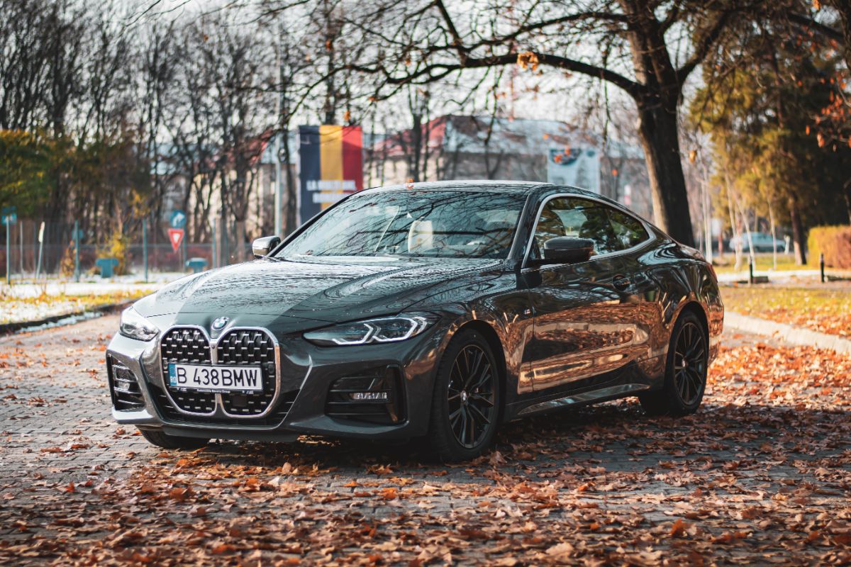 A black bmw 4 seiries photographed at the side of the road fall season.