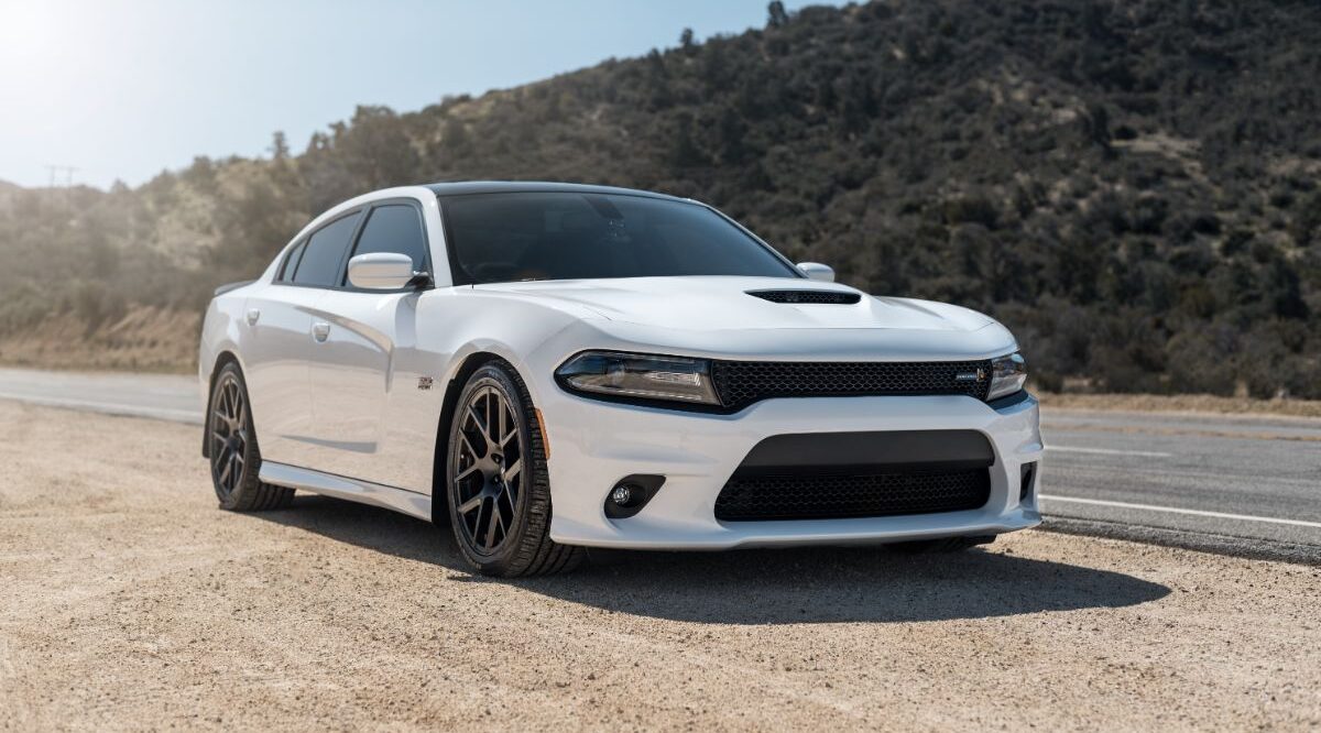 A white dodge challenger parked at the side of road.