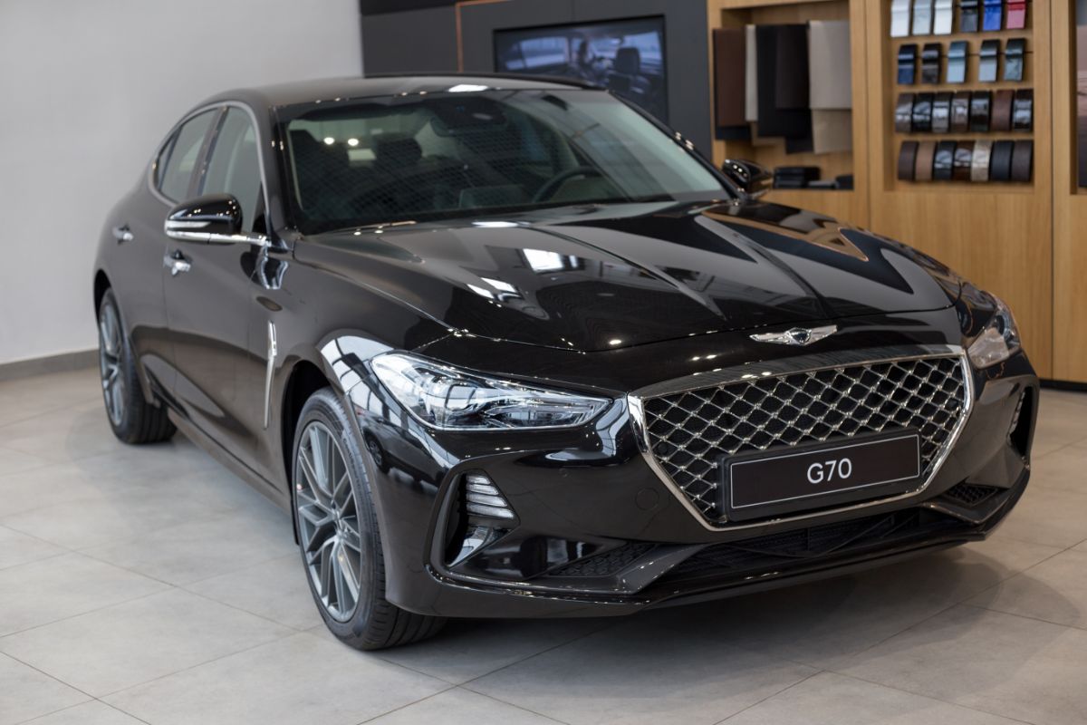 Close up photo of black genesis g70 car inside the building.