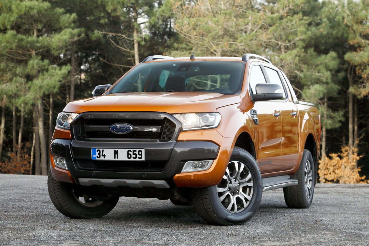 A front view of an orange Ford Ranger in an asphalt road.