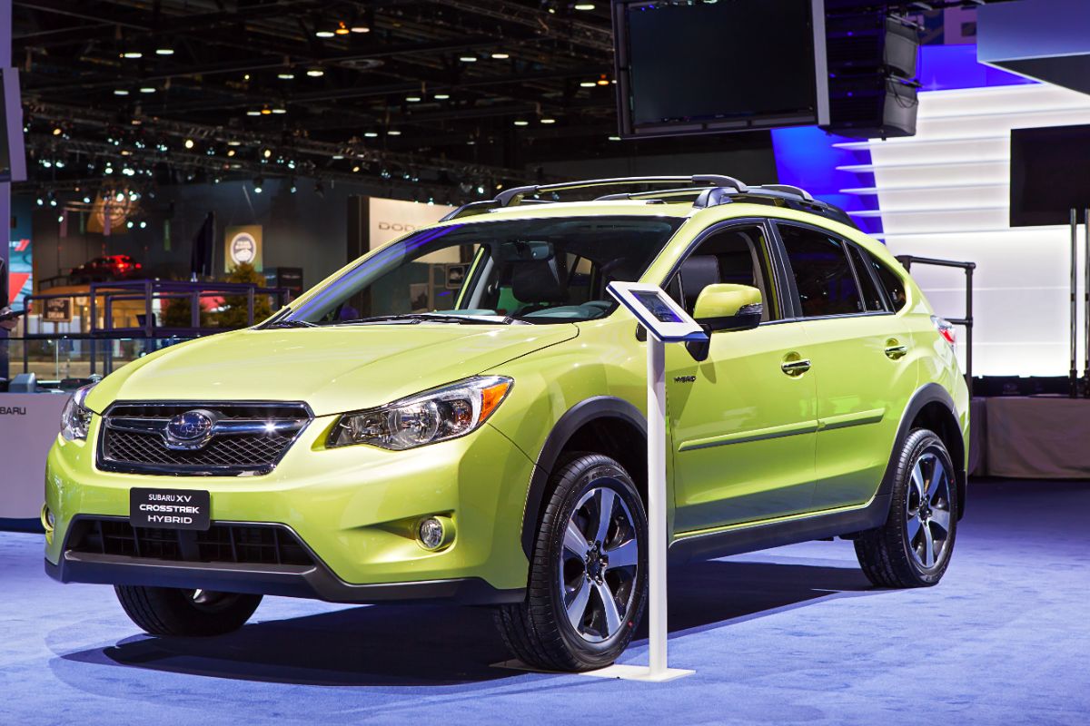 A light yellow subaru crosstrek hybrid on a show spotlighted.