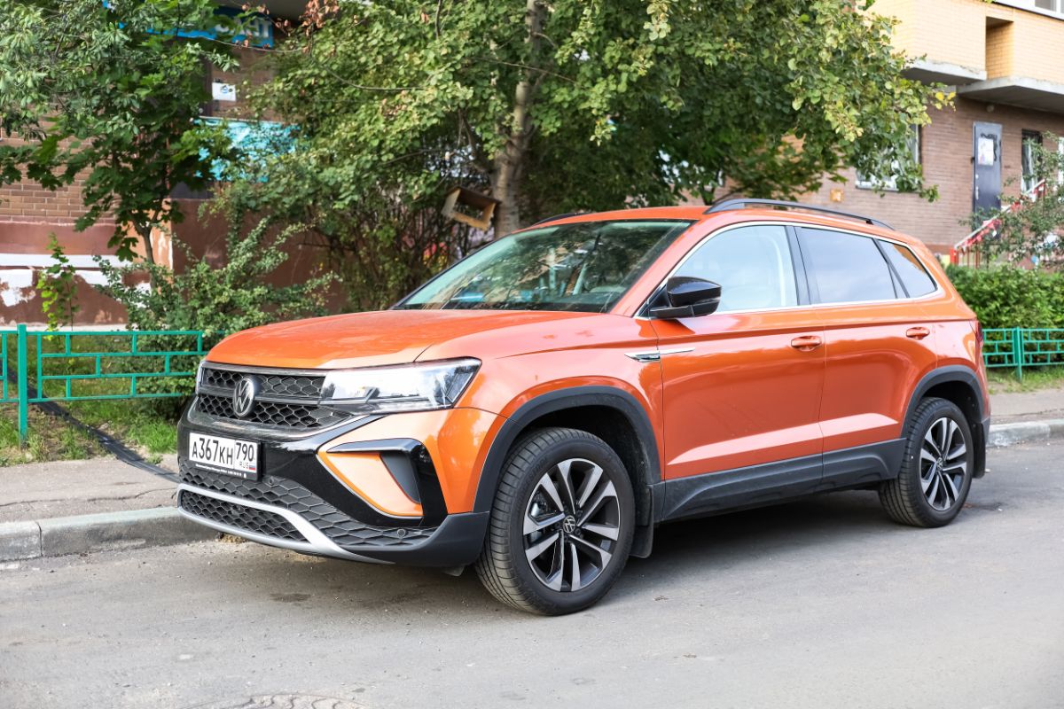 A orange volkswagen taos car on the street parked.