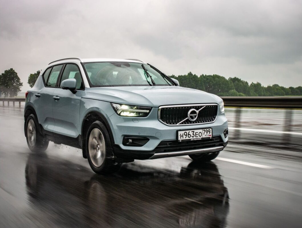 A silver volvo xc40 moving on a wet road.