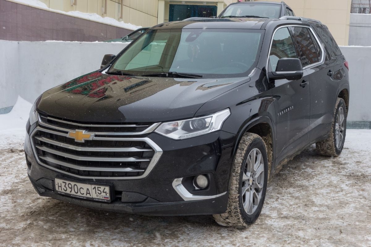 Close up ohoto of black chevrolet traverse car with dirty tire.