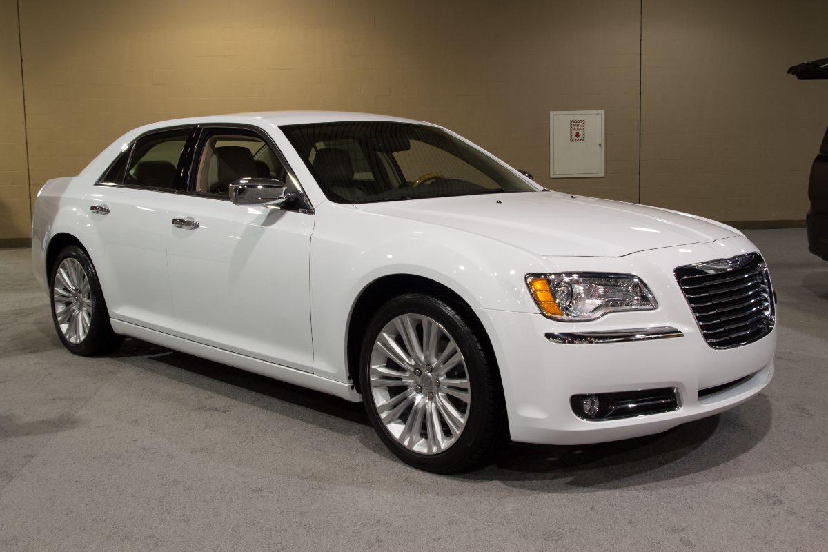 A white chrysler 300 photographed in a car show room.