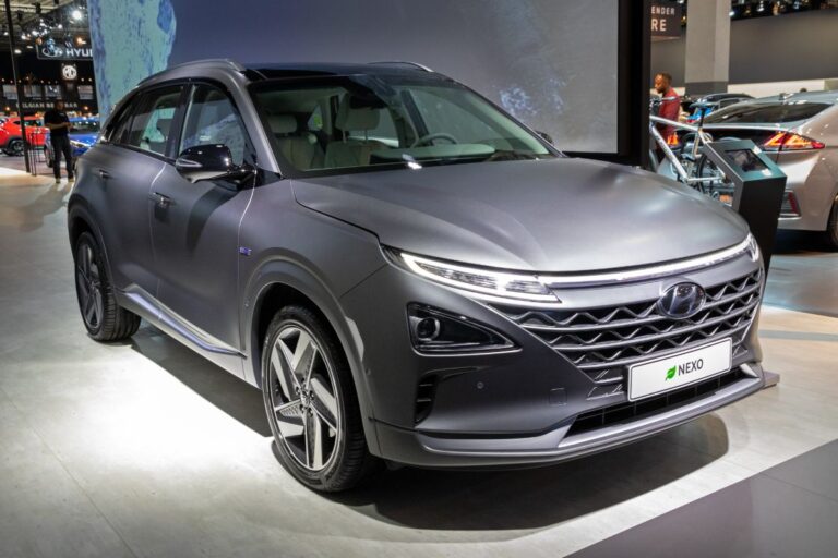 A photo of grey hyundai nexo spotlighted in a car show.