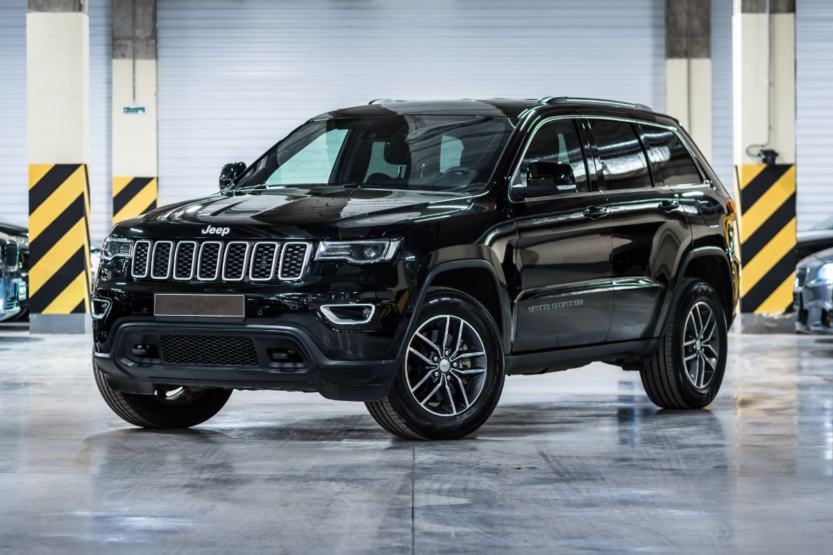 A black jeep grand cherokee in the basement parking lot side view.