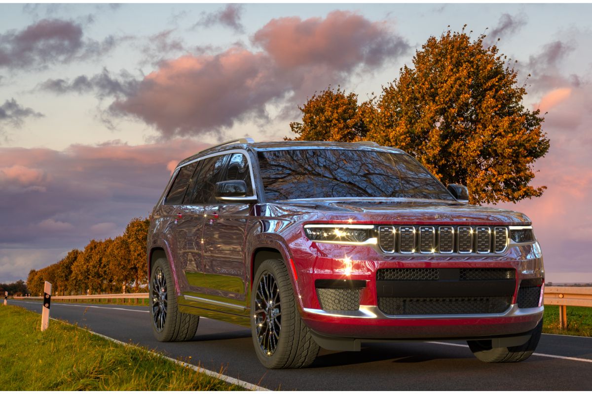 A red jeep grand cherokee l driving in the countryside road.