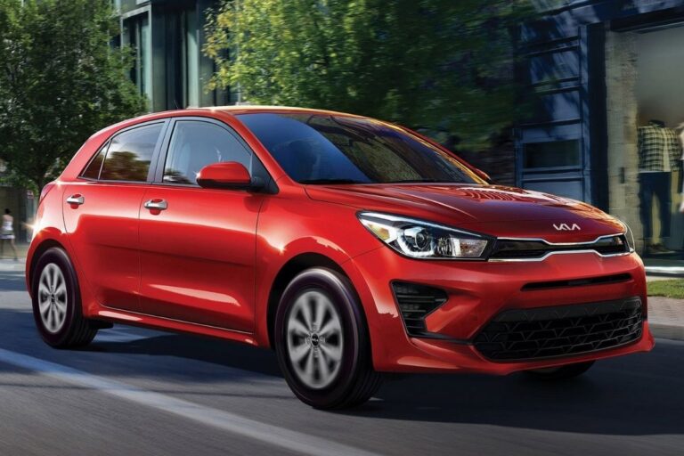 A red shiny kia rio car moving in the city street.