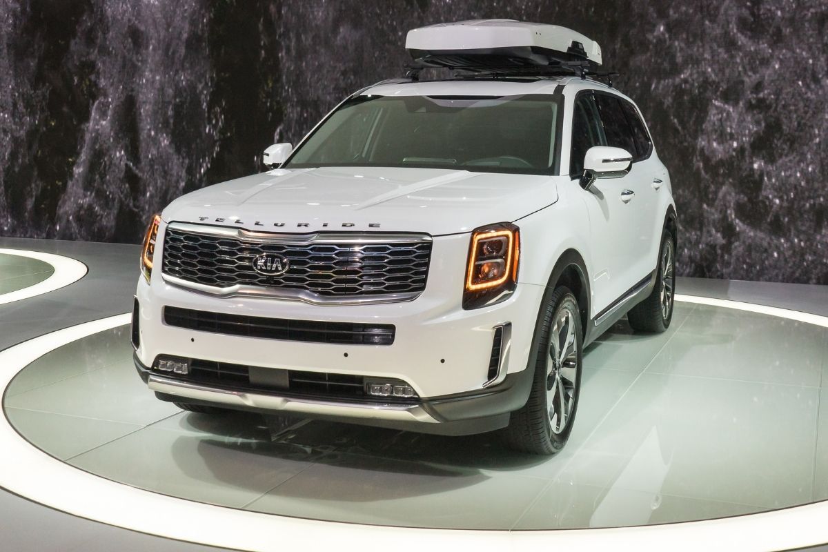 Front view of kia telluride spotlighted in a car show.