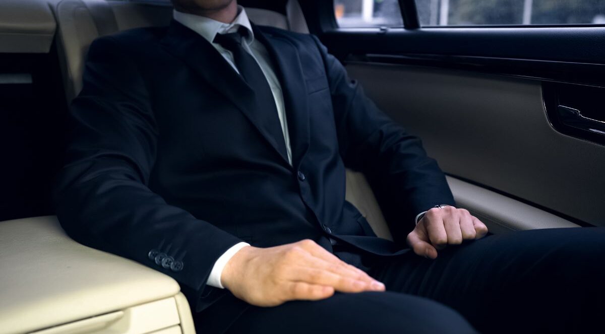 A man in suit sitting on backseat of car.