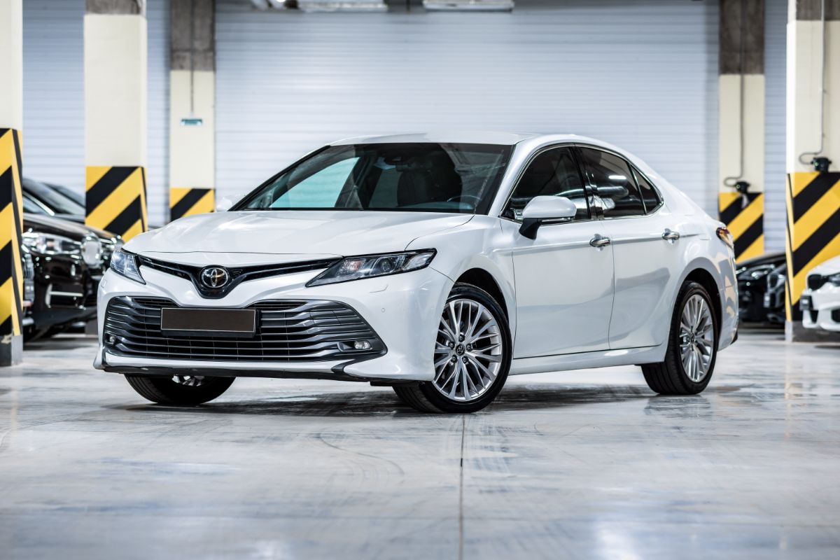 A white toyota camry parked in the underground parking lot.