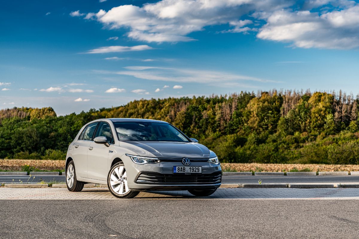 A distant photo of volkswagen golf car photographed daylight with a nature background.